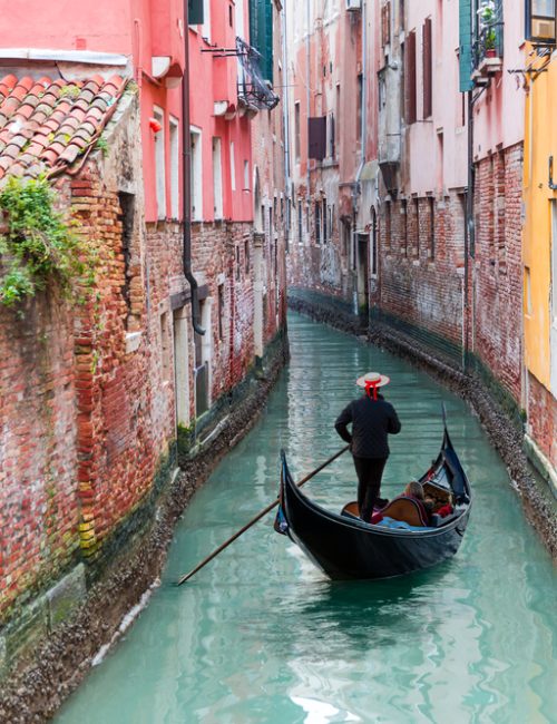 Venetian,Gondolier,Punting,Gondola,Through,Green,Canal,Waters,Of,Venice,